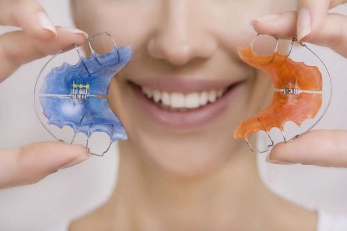 young lady holding two retainers on her hands